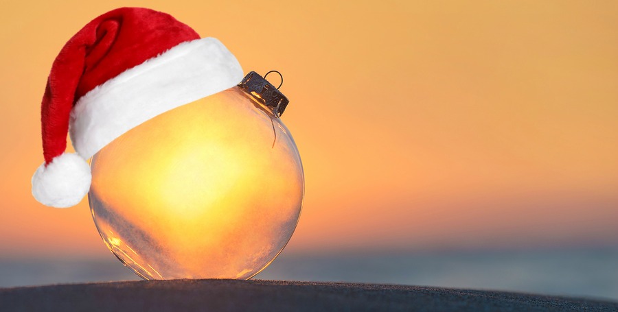 Christmas-tree decoration transparent glass ball at sunset time ocean beach - xmas and New Year vacation in hot countries concept