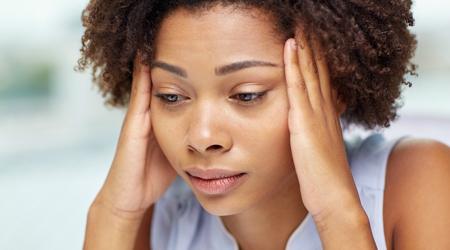 people, emotions, stress and health care concept - unhappy african american young woman touching her head and suffering from headache