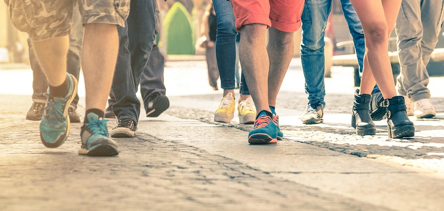 Crowd of people walking on the street - Detail of legs and shoes moving on sidewalk in city center - Travellers with multicolor clothes on vintage filter - Shallow depth of field with sunflare halo