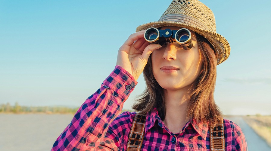 Traveler young woman looking through binoculars outdoor. Space for text in left part of image