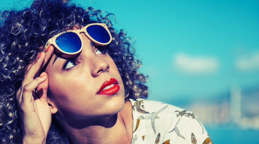 Portrait of adorable mixed race girl raises sunglasses and looking up at sky